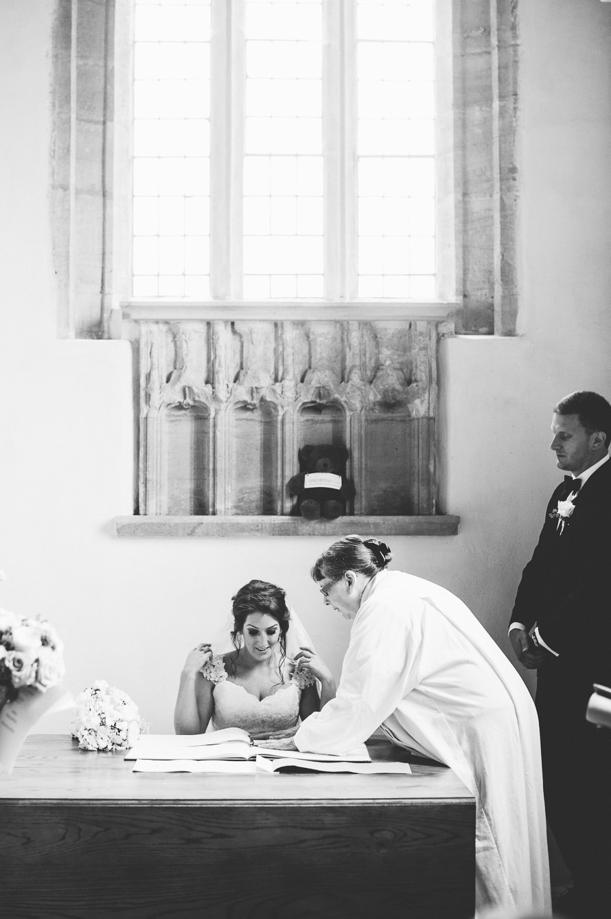 A bride signing the register at Clearwell Castle, photographed in soft window light.